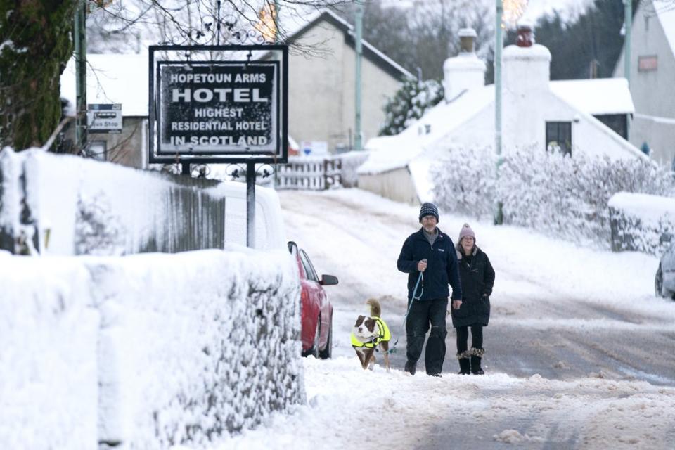 A couple walk their dog through the snow in Leadhills, South Lanarkshire, as Storm Barra hit the UK (Jane Barlow/PA) (PA Wire)