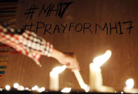 A boy lights candles at a candlelight vigil for passengers killed on Malaysian Airlines flight MH17 in Klang valley July 19, 2014. REUTERS/Olivia Harris