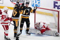 Pittsburgh Penguins' Reilly Smith (19) celebrates his goal with Rickard Rakell (67) as Detroit Red Wings goaltender Alex Lyon (34) collects himself during the first period of an NHL hockey game in Pittsburgh, Sunday, March 17, 2024. (AP Photo/Gene J. Puskar)