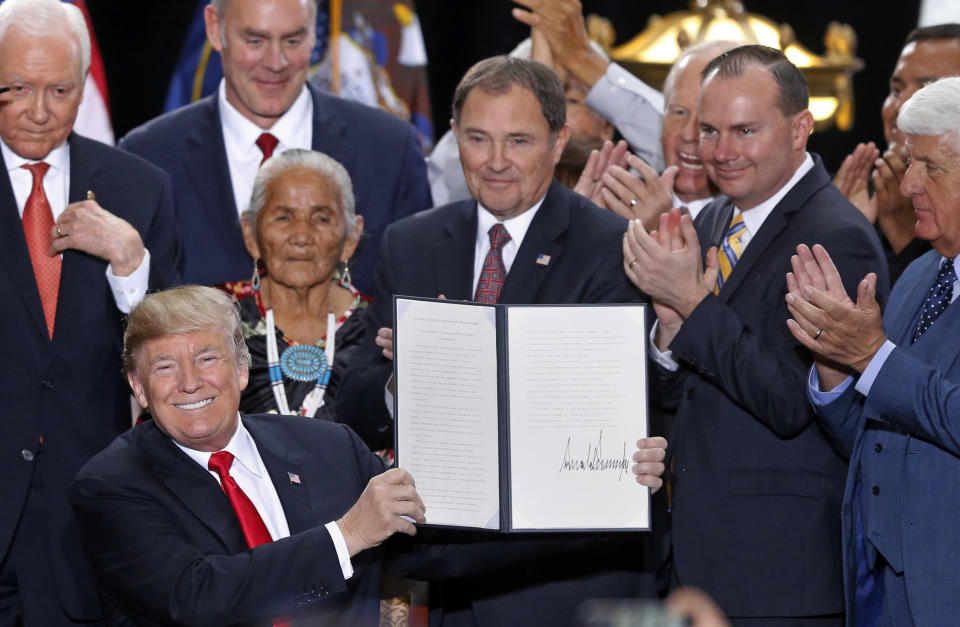 FILE - In this Dec. 4, 2017, file photo, President Donald Trump holds up a signed proclamation to shrink the size of Bears Ears and Grand Staircase Escalante national monuments at the Utah State Capitol, in Salt Lake City. A federal judge has rejected the Trump administration's bid to dismiss lawsuits challenging the constitutionality of a 2017 decision to downsize two sprawling national monuments in Utah. (AP Photo/Rick Bowmer, File)