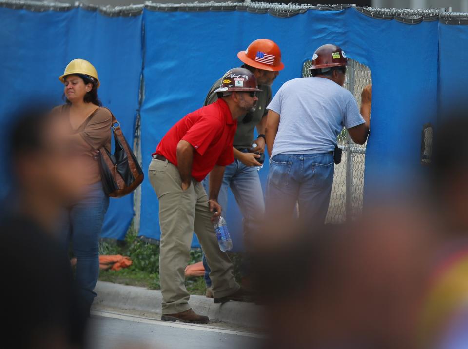 DORAL, FL - OCTOBER 10: Construction workers watch as search and rescue people look for possible survivors in the rubble of a four-story parking garage that was under construction and collapsed at the Miami Dade College’s West Campus on October 10, 2012 in Doral, Florida. Early reports indicate that one person was killed, at least seven people injured and an unknown number of people may be buried in the rubble. (Photo by Joe Raedle/Getty Images)