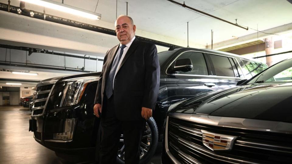 bald limo driver stands with cadillac cars in parking garage