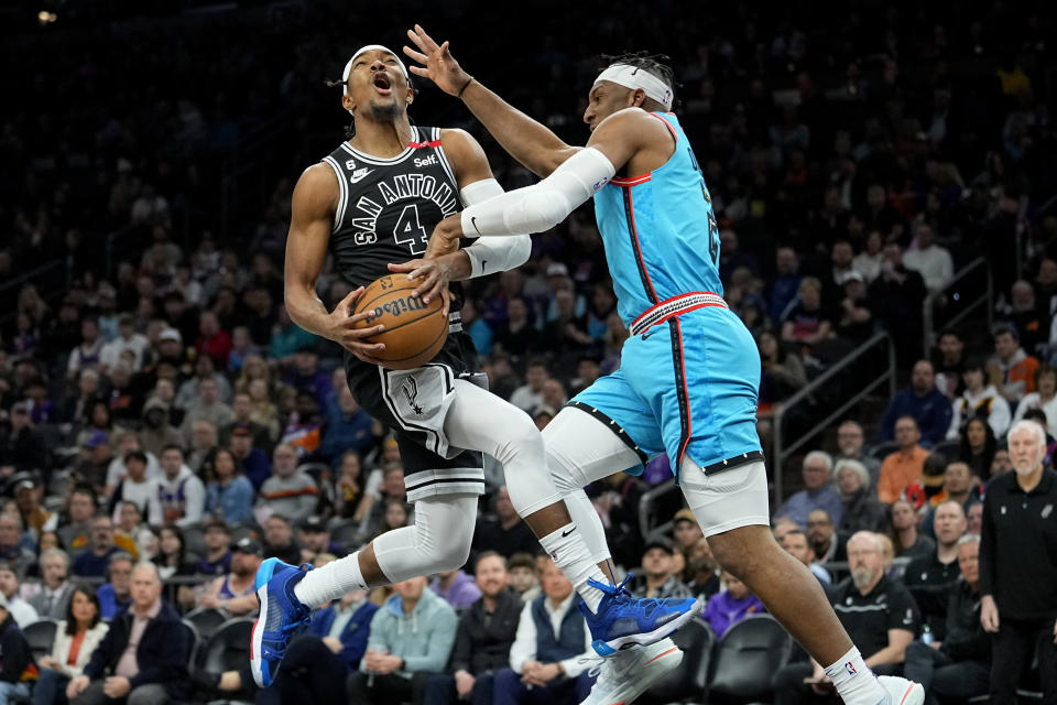 San Antonio Spurs guard Devonte' Graham (4) is fouled by Phoenix Suns forward Josh Okogie during the first half of an NBA basketball game, Tuesday, April 4, 2023, in Phoenix. (AP Photo/Matt York)