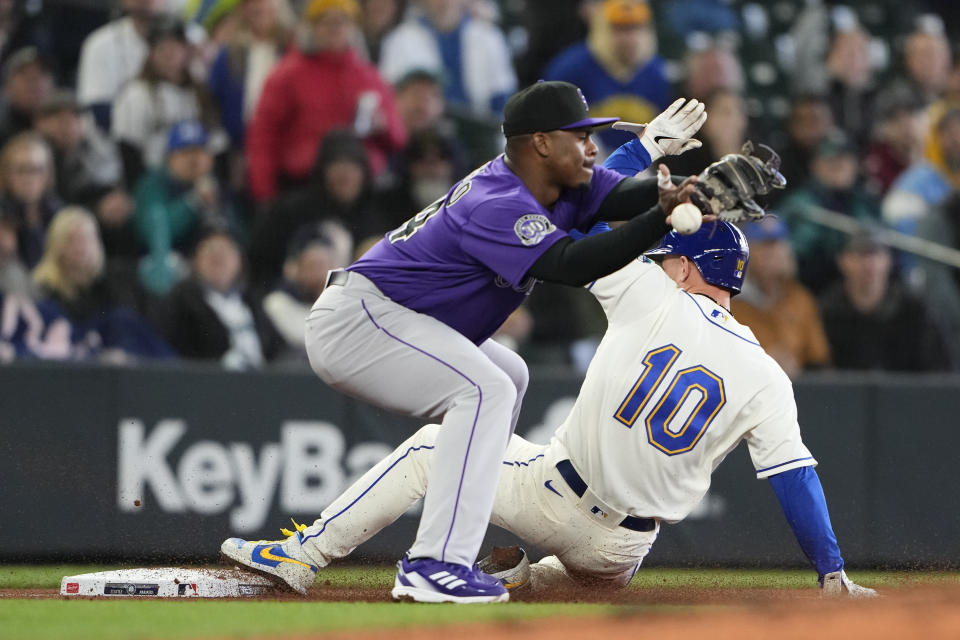 Seattle Mariners' Jarred Kelenic reaches third base on an error by Colorado Rockies catcher Brian Serven as third baseman Elehuris Montero misses the throw during the fifth inning of a baseball game, Sunday, April 16, 2023, in Seattle. (AP Photo/Lindsey Wasson)