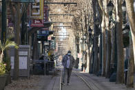 A pedestrian wears a mask while standing on train tracks during the coronavirus pandemic in San Jose, Calif., Tuesday, Dec. 1, 2020. (AP Photo/Jeff Chiu)