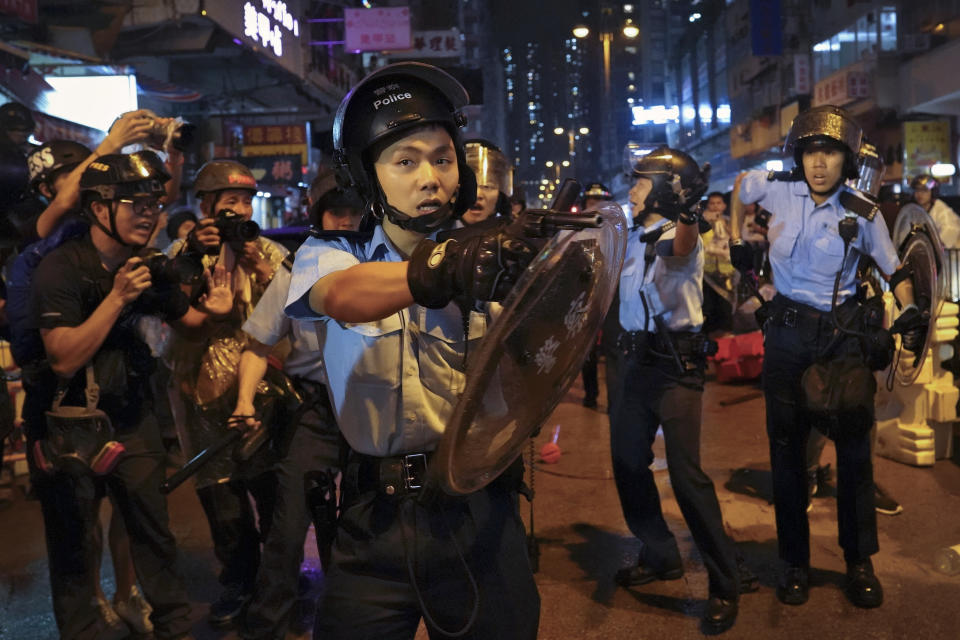 A policeman points his gun after confronting demonstrators during a protest in Hong Kong, Sunday, Aug. 25, 2019. Hong Kong police have rolled out water cannon trucks for the first time in this summer's pro-democracy protests. The two trucks moved forward with riot officers Sunday evening as they pushed protesters back along a street in the outlying Tsuen Wan district. (AP Photo/Vincent Yu)