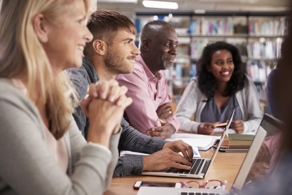 group of mature college students collaborating on project in the library