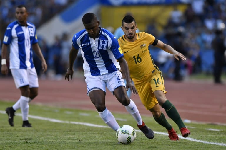 Honduras' Brayan Beckeles (C) drives the ball past Australia's Aziz Behich during their FIFA 2018 World Cup qualifying play-off first leg match, in San Pedro Sula, Honduras, on November 10, 2017