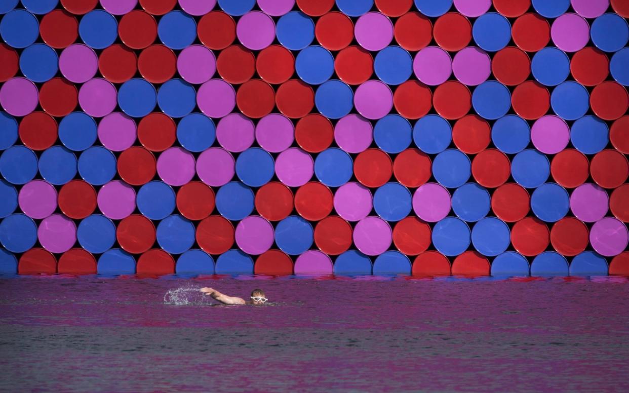 A swimmer passes Christo's giant sculpture, the London Mastaba, in Hyde Park - London News Pictures Ltd