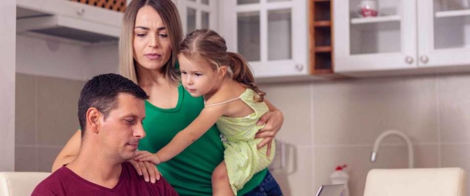 Young family dealing with financial issues - looking at bills at the kitchen table.