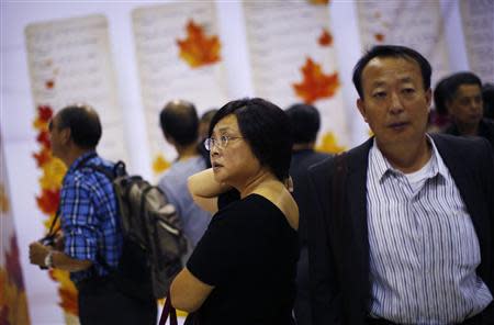 A woman looks at signs showing the personal profiles of people looking for spouses during a matchmaking event for middle-aged singles and seniors, sponsored by Shanghai's government, in Shanghai November 9, 2013. REUTERS/Carlos Barria