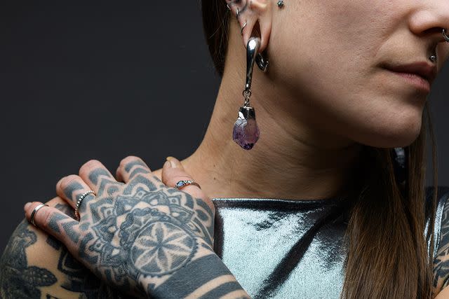 <p>Getty</p> A stock image of a person with tattoos and piercings