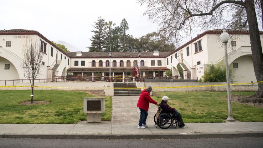 A man pushes a woman in a wheelchair past the Veterans Home of California in Yountville in 2018.