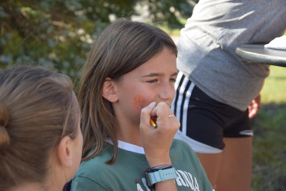 Marlee Pletcher, 9, sits to have a basketball drawn on her face at the 2023 Timberwolves Athletic Rally on Sept. 23, 2023. Pletcher's older brother plays on the North Central Michigan College basketball team.