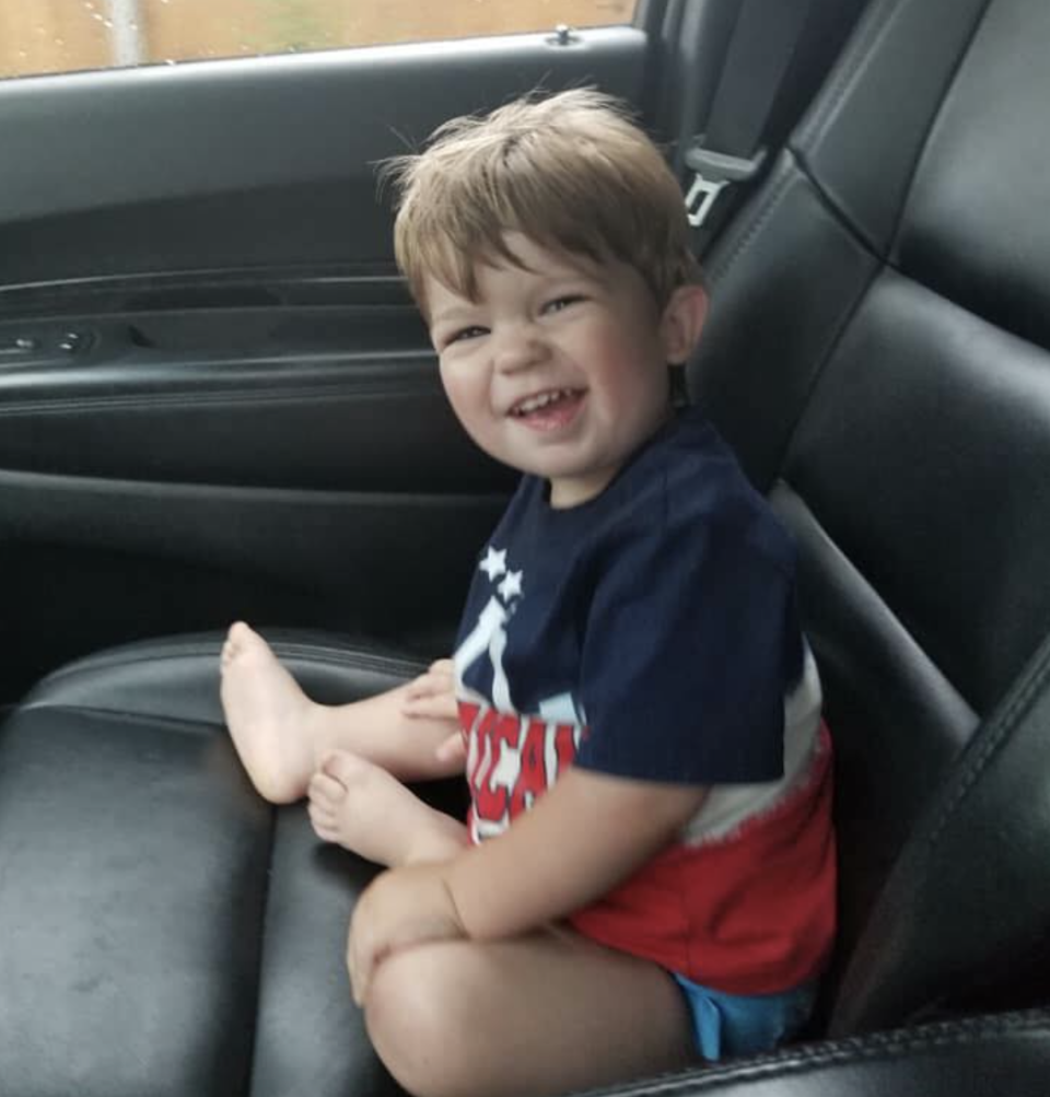 Photo shows Caleb smiling while sitting in a car seat.