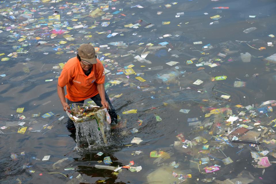 <p>An activist collects plastic bags and other types of garbage from the Manila Bay on July 3, 2014.</p>