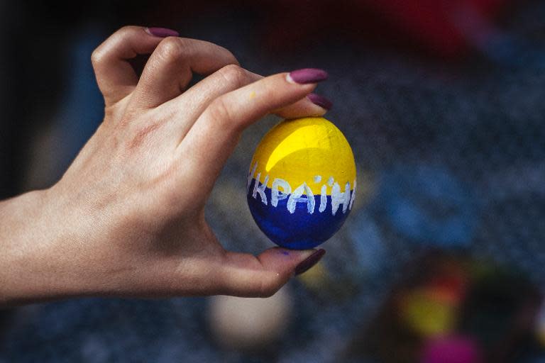 A woman holds a wooden Easter egg painted with the colors of the Ukrainian flag during a pro-Ukrainian rally in the eastern Ukrainian city of Lugansk, on April 19, 2014