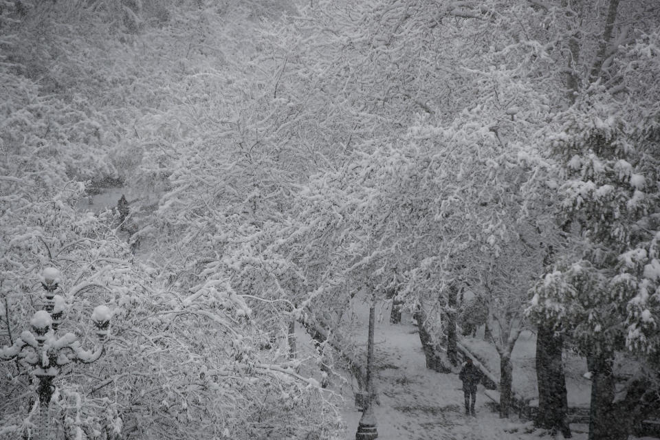 Pedestrians walk outside the snow covered National Garden in central Athens, Tuesday, Feb.16, 2021. Unusually heavy snowfall has blanketed central Athens, with authorities warning residents particularly in the Greek capital's northern and eastern suburbs to avoid leaving their homes. (AP Photo/Thanassis Stavrakis)