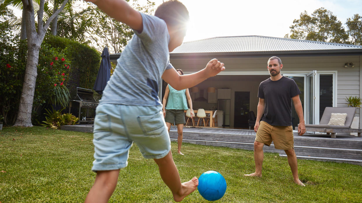 Australian kid playing with parents in the back yard garden.