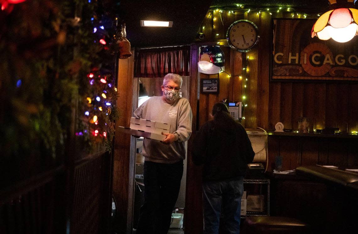 Zelda’s Original Gourmet Pizza owner Kerry Matthews — son of the late Zelda Breslin, who opened the in midtown Sacramento restaurant in 1979 — walks a stack of Chicago-style deep dish pizza pies to the side door for takeout as coronavirus prevention measures are in place in 2020.