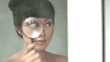 A woman looks through a magnifying glass