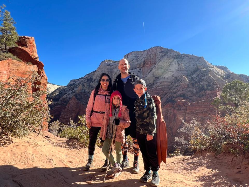 A family of four posing during a hike in an area with red rocks.