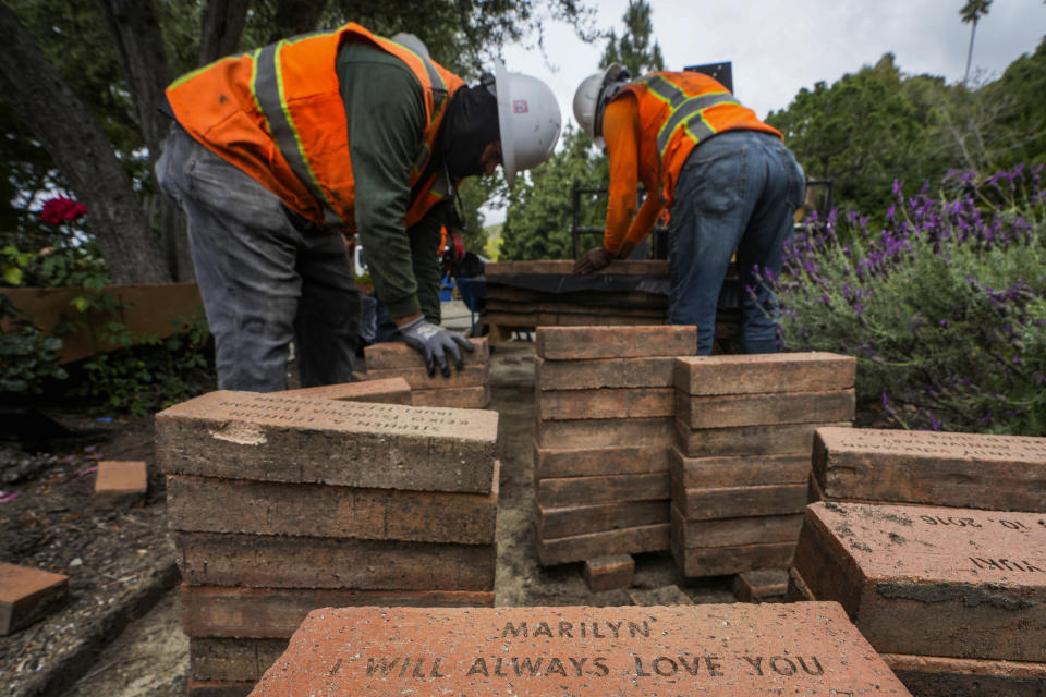 Workers remove bricks stamped with past members' names from a garden path at Wayfarers Chapel, known as "The Glass Church," in Rancho Palos Verdes, Calif., Wednesday, May 15, 2024. The modernist chapel features organic architecture with glass walls in a redwood grove overlooking the Pacific Ocean. The Wayfarers Chapel was designed by architect Lloyd Wright, son of Frank Lloyd Wright, and completed in 1951. Wayfarers Chapel management announced plans to disassemble the iconic structure to save it from landslide destruction. (AP Photo/Damian Dovarganes)