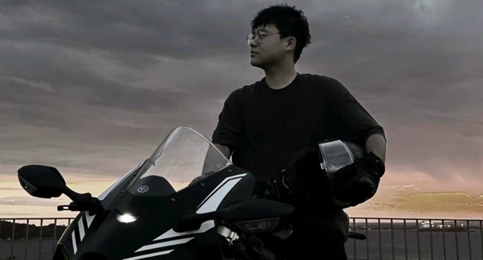 International student Gordon Wang poses with his motorbike helmet under his arm while straddling a motorbike. He died in a motorbike crash outside UNSW, Sydney. 