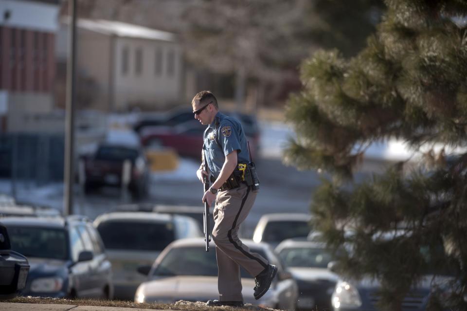 An armed Arapahoe police officer walks outside Arapahoe High School, after a student opened fire in the school in Centennial, Colorado