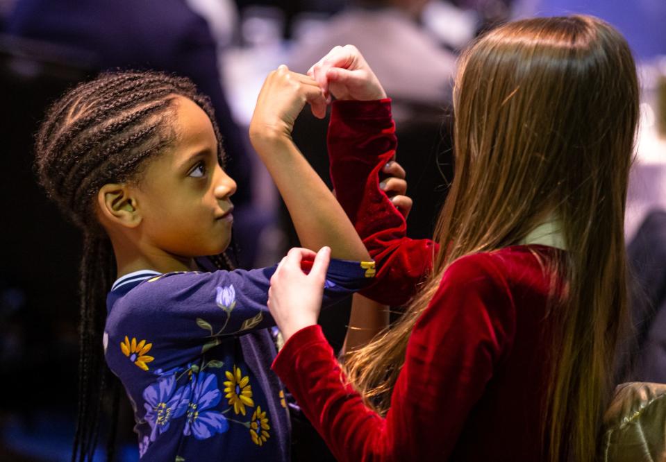 Taylor Colliar, 6, left, and Mia Bogel, 9, try to create a heart using both their arms from an image they saw in the program during the annual Springfield Frontiers International Club Dr. Martin Luther King Jr. Memorial Breakfast at the Wyndham Springfield City Centre on Jan. 20, 2020.