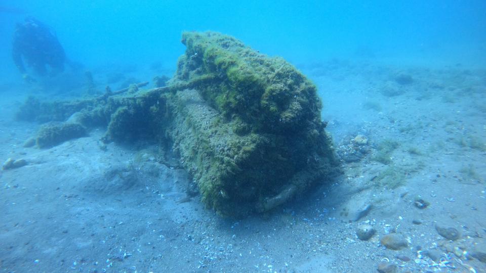 We see a piece of the plane underwater. A diver is behind it.