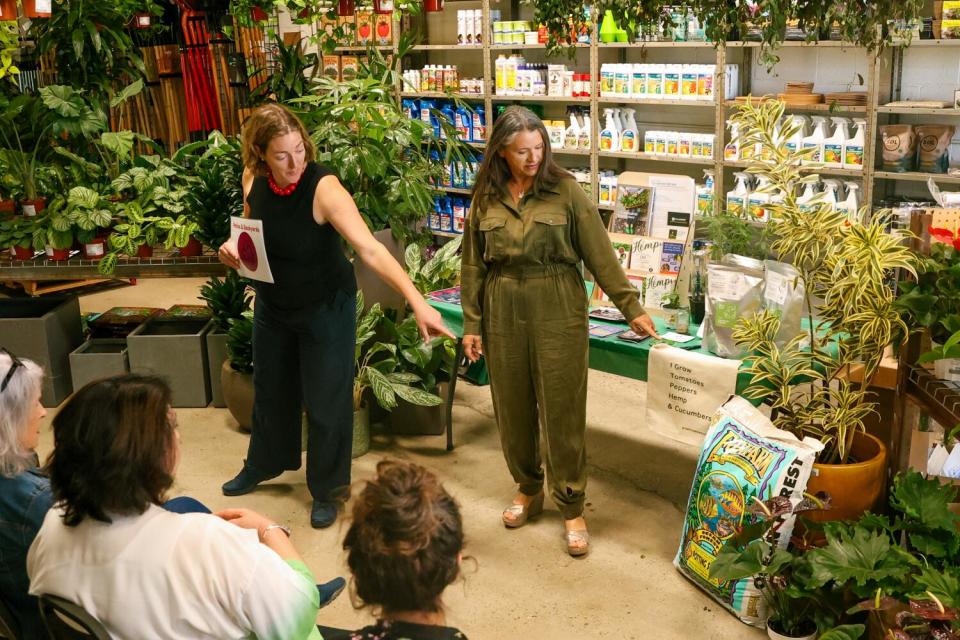 Two people point to a bag of potting soil.