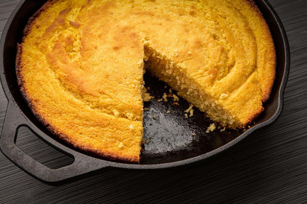 Fresh corn bread right out of the oven baked in a cast iron skillet with a slice removed