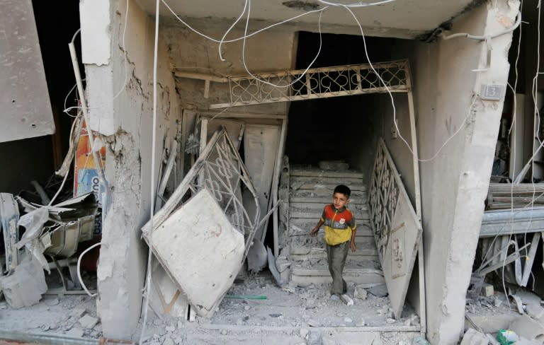 A Syrian child walks out of damaged building following an air strike on the rebel-held town of Arbin, east of the capital, on July 22