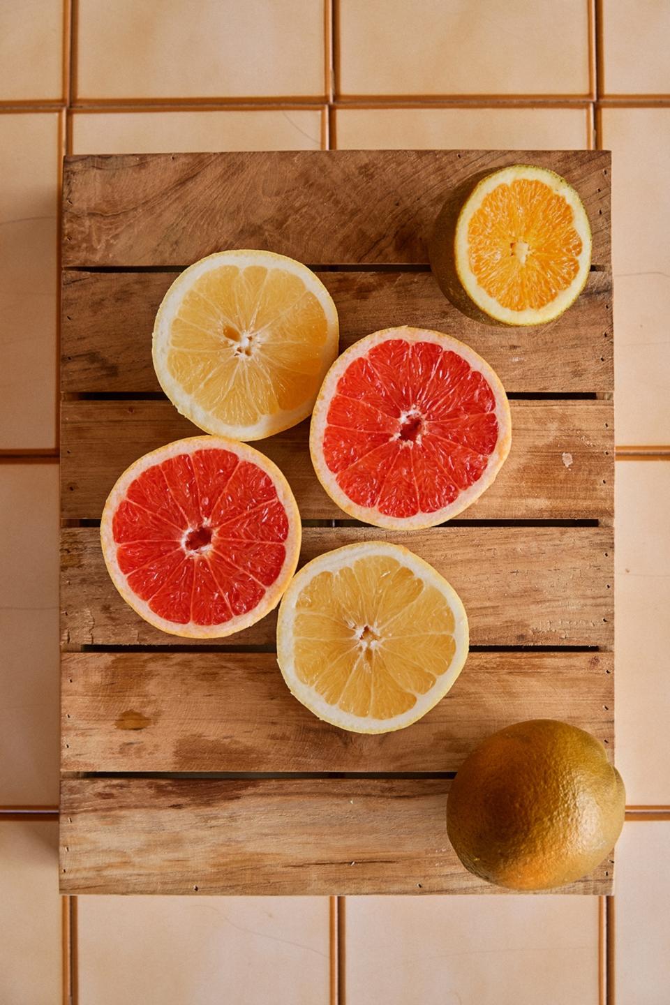 Insides of pink and yellow citrus fruit on a wooden chopping board