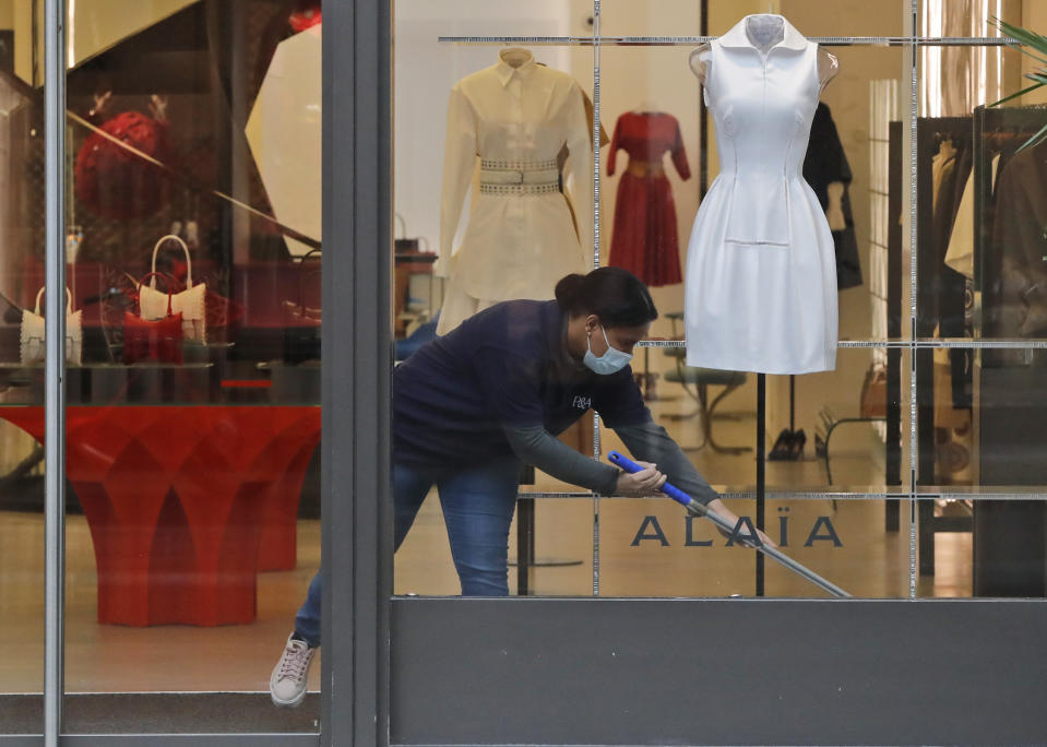 A woman wearing a face covering due to the COVID-19 pandemic cleans inside a shop during lockdown in London, Wednesday, Feb. 17, 2021. (AP Photo/Frank Augstein)