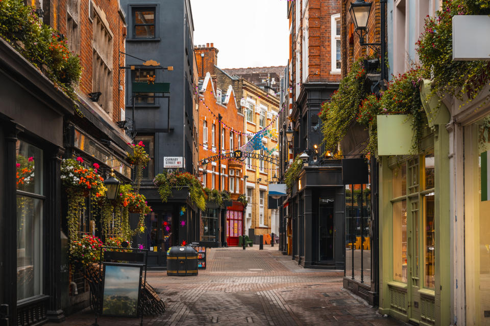 Charming street with historical buildings, hanging flowers, and a clear daytime sky. No people are visible