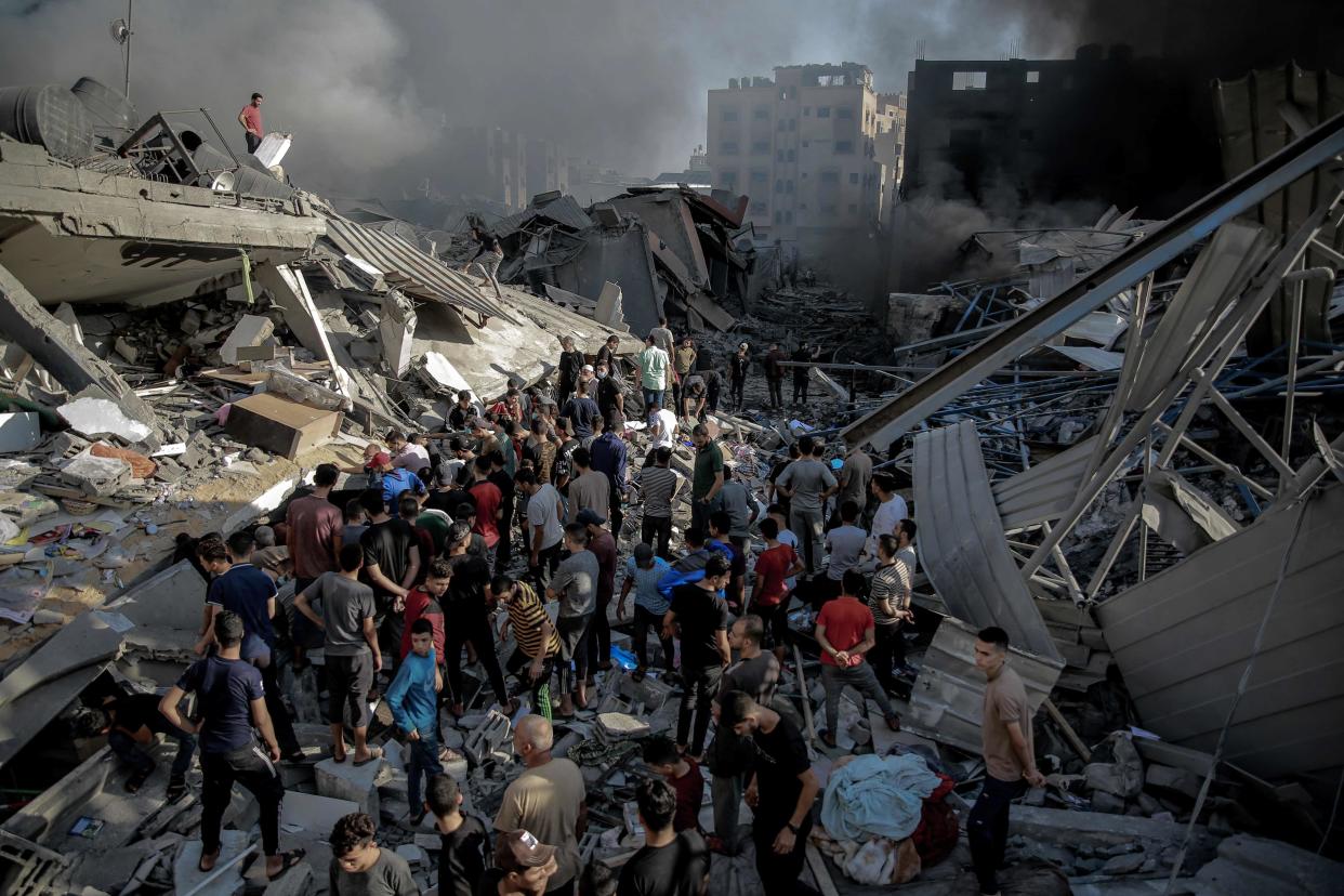 People gather amid the destruction in the aftermath of an Israeli strike on Gaza City on 26 October 2023, as battles continue between Israel and the Palestinian Hamas group (AFP via Getty Images)