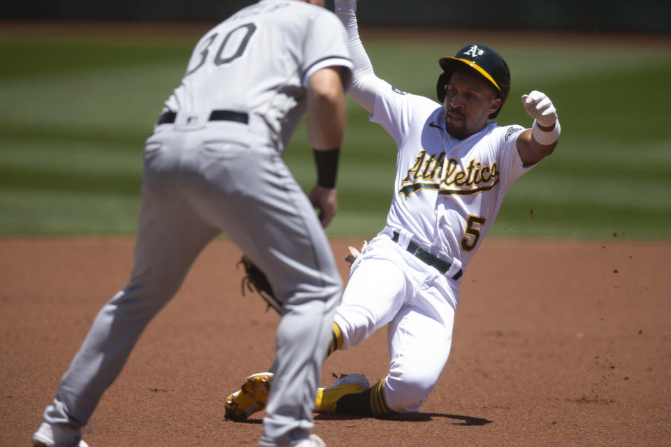 Oakland Athletics' Tony Kemp (5) slides safely into third base with a triple ahead of the relay to Chicago White Sox third baseman Jake Burger (30) during the first inning of a baseball game, Saturday, July 1, 2023, in Oakland, Calif. (AP Photo/D. Ross Cameron)