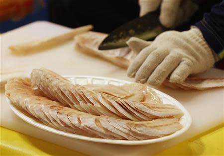 A fish dealer slices frozen pollack at his store at a market in central Seoul September 13, 2013. REUTERS/Lee Jae-Won