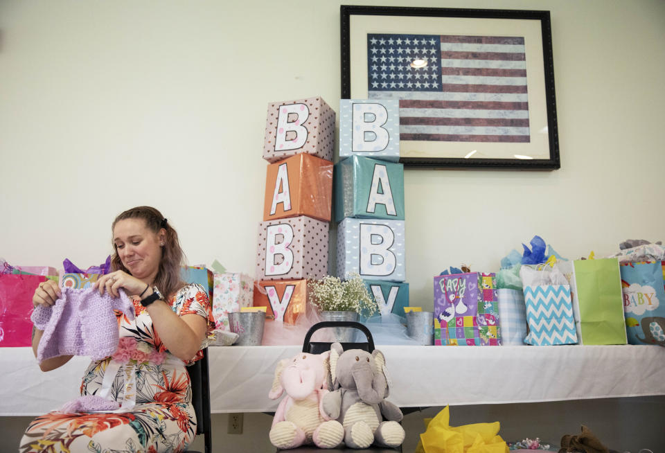 Krista Johnston opens gifts during a baby shower at the American Legion hall in Trumansburg, N.Y., Sunday, Sept. 1, 2019. Krista's husband, Sgt. James Johnston, was killed in Afghanistan in June. When Krista delivered the news to him that she was pregnant, he stared at the message, then turned around with tears rolling down his face. "It was the first time I'd see him cry in the seven years we'd been together," she recalls. She cried, too. The next morning, he headed to war. (AP Photo/David Goldman)