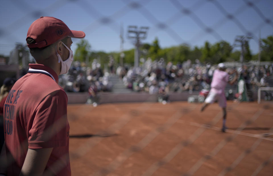 A court attendant wearing a face mask against the coronavirus watches as United States's Reilly Opelka plays a return to Slovakia's Andrej Martin during their first round match on on day two of the French Open tennis tournament at Roland Garros in Paris, France, Monday, May 31, 2021. (AP Photo/Christophe Ena)