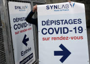 A man puts up a poster for COVID-19 testing at Lille Zenith Arena in Lille, northern France, Thursday, Oct. 15, 2020. French President Emmanuel Macron has announced that millions of French citizens in several regions around the country, including in Paris, will have to respect a 9pm curfew from this Saturday until Dec. 1. It's a new measure aimed at curbing the resurgent coronavirus amid second wave. (AP Photo/Michel Spingler)
