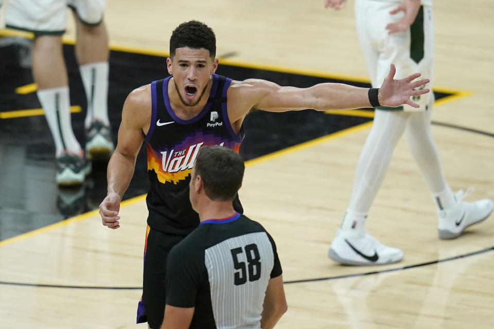 Phoenix Suns guard Devin Booker, top, gestures while talking with referee Josh Tiven (58) during the second half of Game 5 of basketball's NBA Finals between the Suns and the Milwaukee Bucks, Saturday, July 17, 2021, in Phoenix. (AP Photo/Ross D. Franklin)