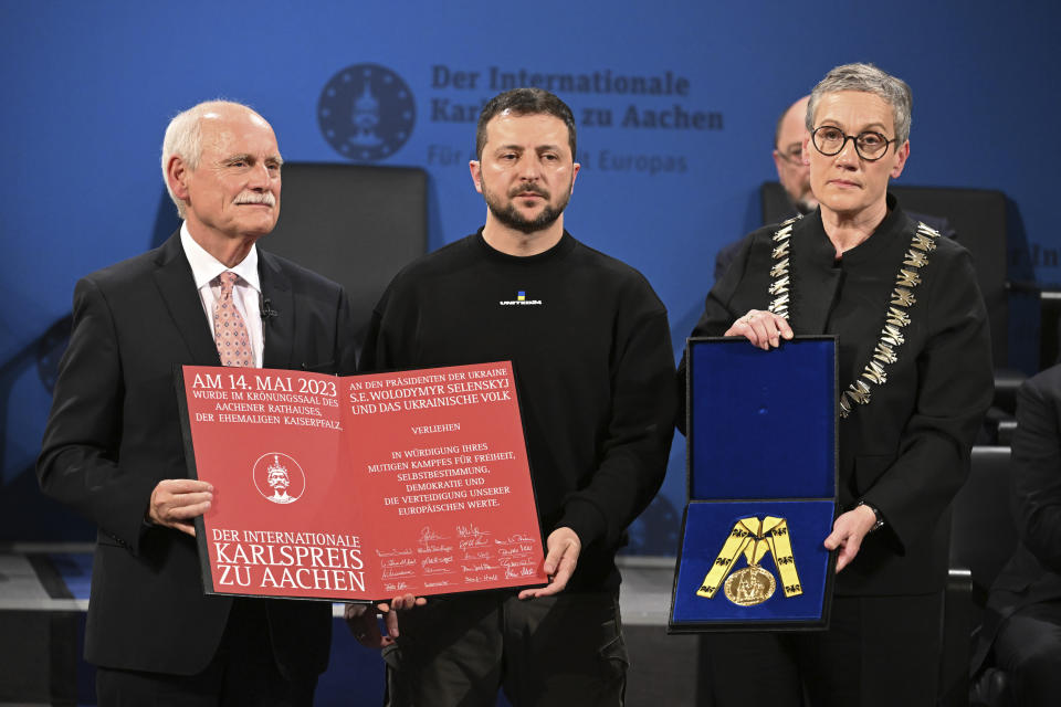 Ukrainian President Volodymyr Zelenskyy, center, receives the Charlemagne Prize for Services to European Unity from the Lord Mayor of Aachen Sibylle Keupen, right, in Aachen, Germany, Sunday, May 14, 2023. Zelenskyy is in Aachen to receive the International Charlemagne Prize, awarded to him and the people of Ukraine. (Federico Gambarini/DPA via AP, Pool)