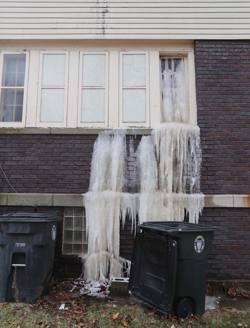 Cascading ice has formed down a back window as running water is heard inside the site of the former funeral home next to the abandoned Akron church of Shawnte Hardin.