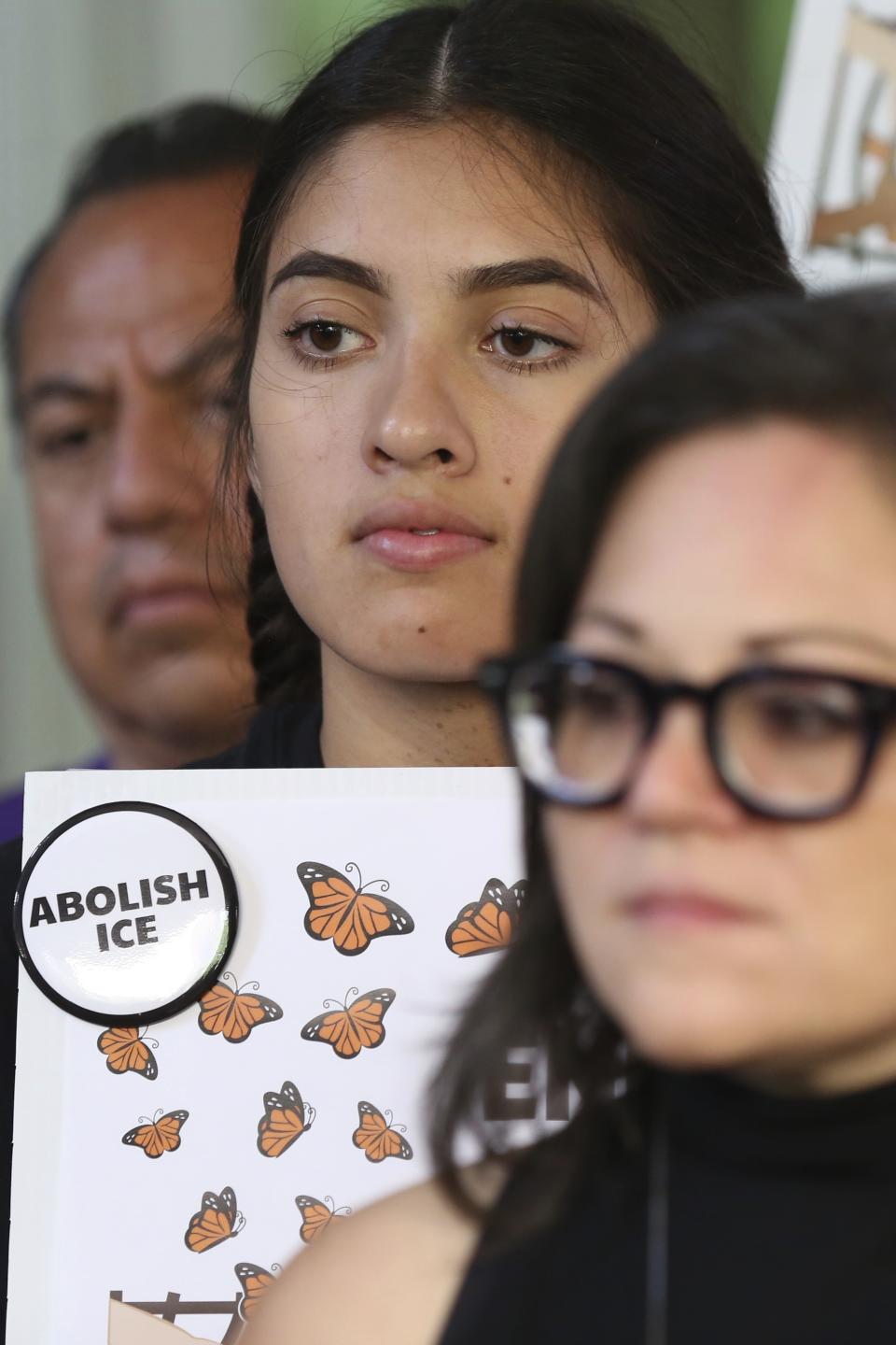 A demonstrators holds a sign Mony Ruiz-Velasco, director of PASO West Suburban Action Project, addresses reporters during a new conference outside the U.S. Citizenship and Immigration Services offices in Chicago, Thursday, July 11, 2019. A nationwide immigration enforcement operation targeting people who are in the United States illegally is expected to begin this weekend. (AP Photo/Amr Alfiky)