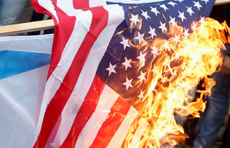 Palestinians burn an Israeli and a U.S. flag during a protest against the U.S. intention to move its embassy to Jerusalem and to recognize the city of Jerusalem as the capital of Israel, in Gaza City December 6, 2017. REUTERS/Mohammed Salem