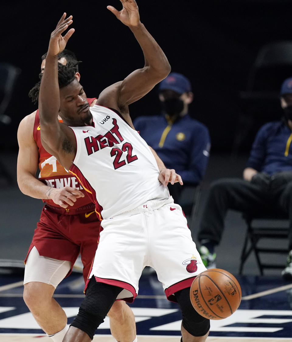 Miami Heat forward Jimmy Butler, front, is fouled by Denver Nuggets guard Facundo Campazzo during the first half of an NBA basketball game Wednesday, April 14, 2021, in Denver. (AP Photo/David Zalubowski)