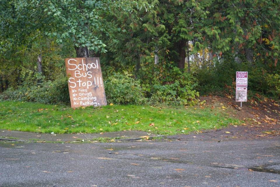 A sign is posted at a school bus stop to promote safety in front of Tullwood Apartments on Oct. 17, 2023, in Bellingham, Wash. The apartments are located next to one of Bellingham’s largest homeless encampments. Rachel Showalter/The Bellingham Herald